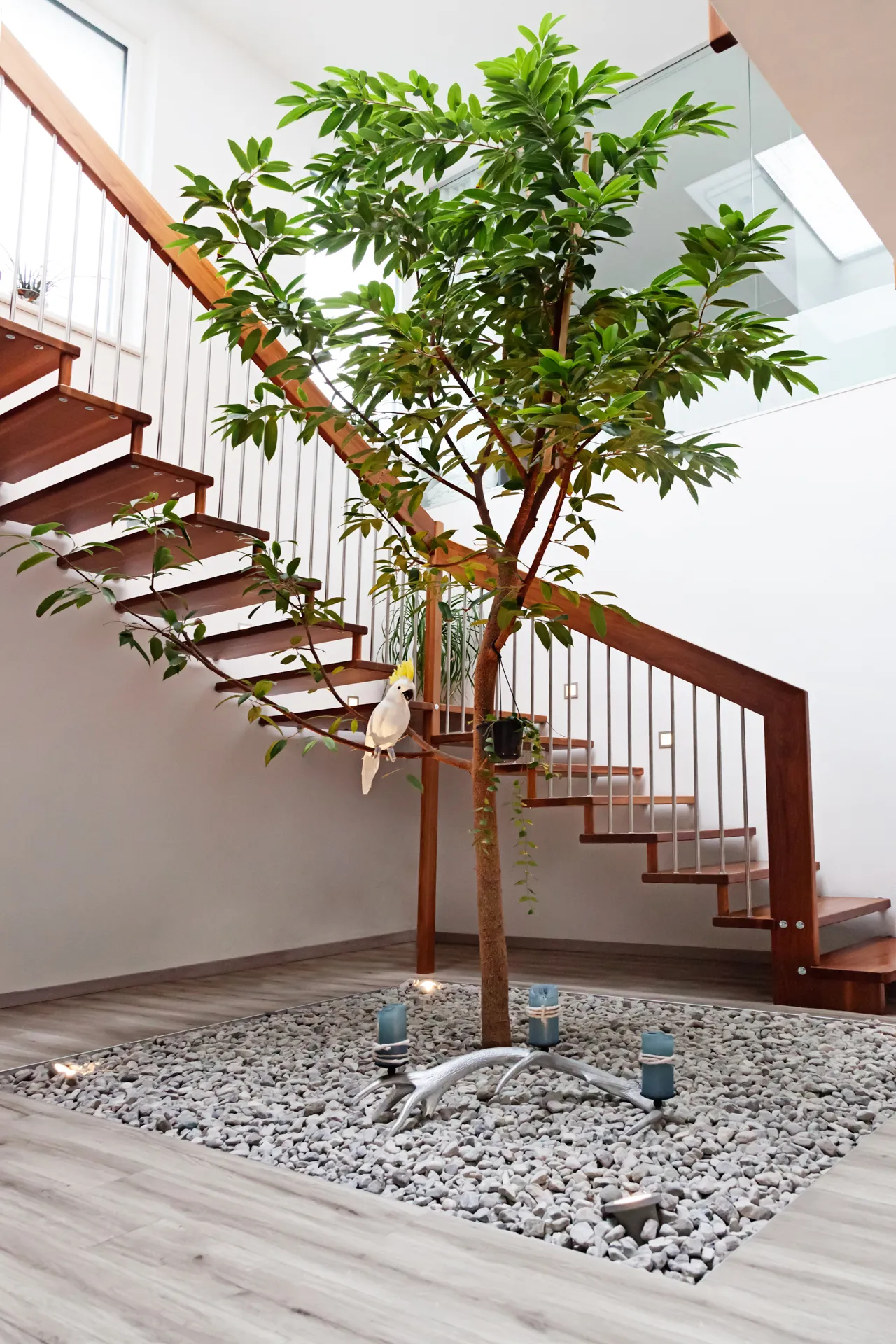 Freitragende Holztreppe neben einem Innenhof mit Baum